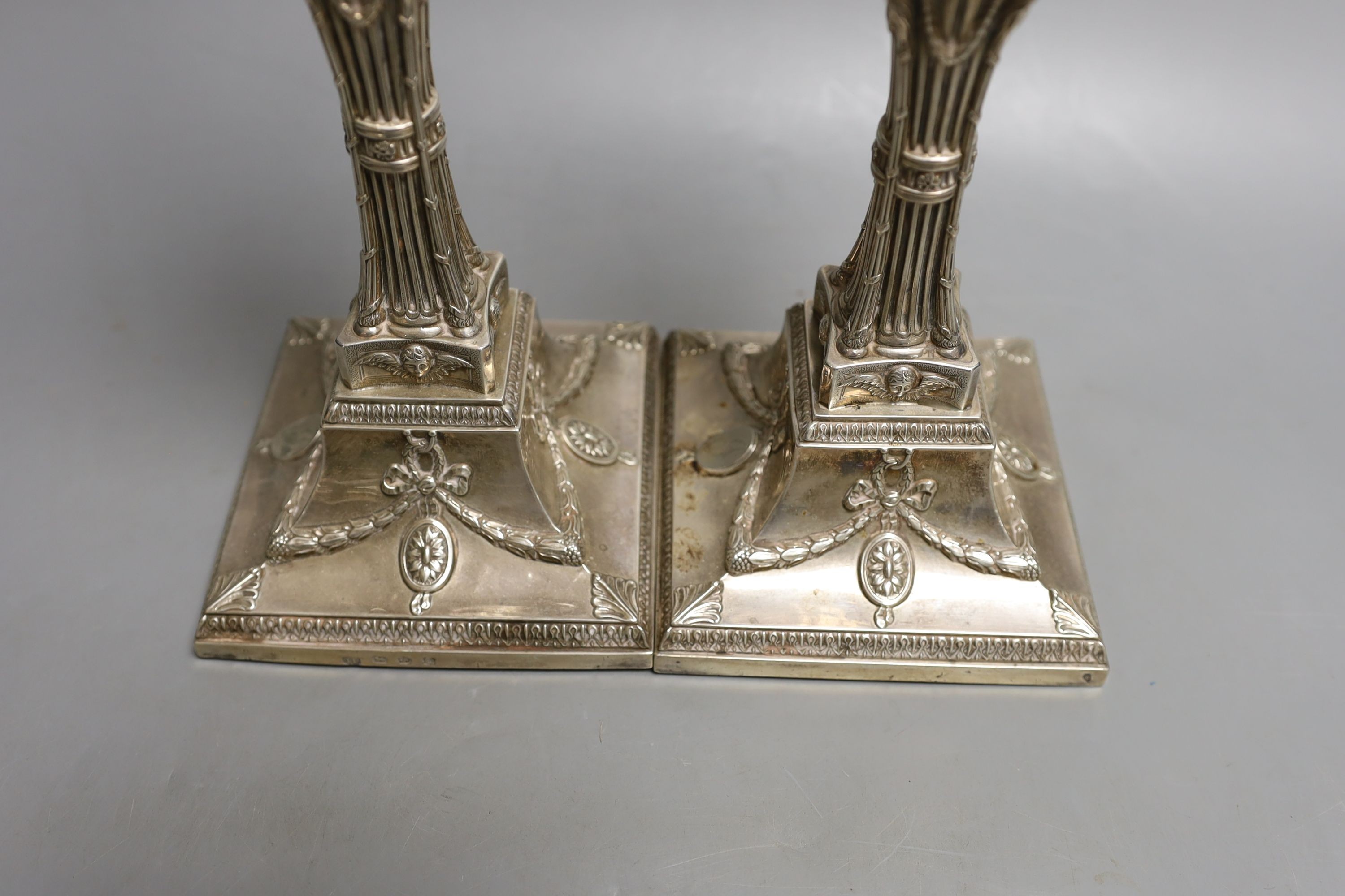A matched pair of George III silver candlesticks, with waisted fluted stems and rams head, winged mask and swag decoration, Joseph Tibbitts, Sheffield, 1775 and George Ashforth & Co, Sheffield, 1775 29.4cm, weighted.